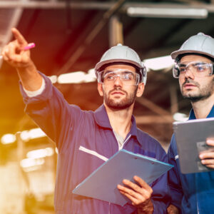 Two engineer worker working together with safety uniform and white helmet to work in industry factory handle tablet.