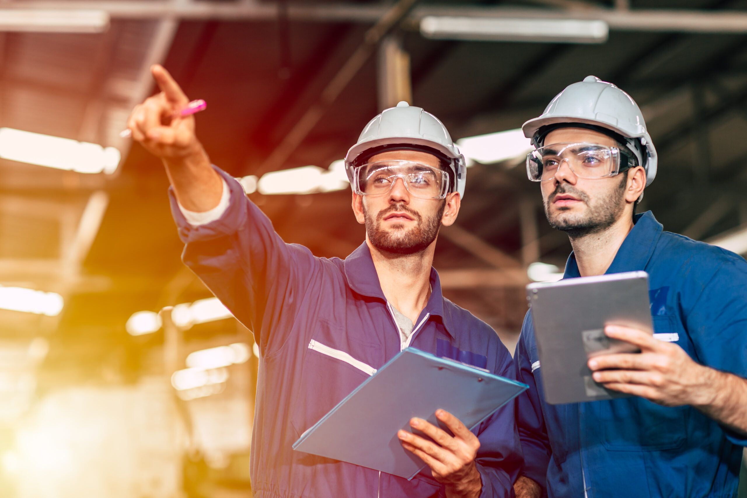 Two engineer worker working together with safety uniform and white helmet to work in industry factory handle tablet.