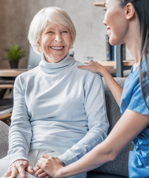 Vertical shot of helpful nurse taking care of senior woman in nursing home